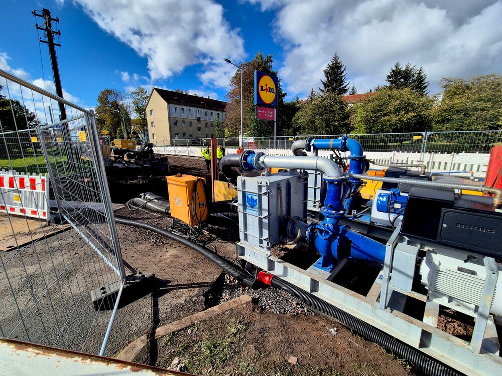 Baustelle mit einem Rohrgraben, Bagger und einer Pumpenanlage